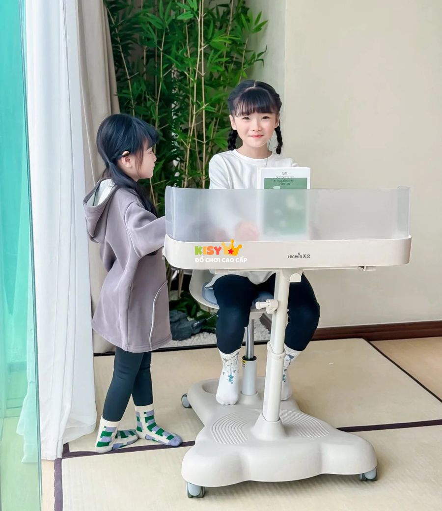 Hai chị em bên bàn học đặt cạnh cửa sổ