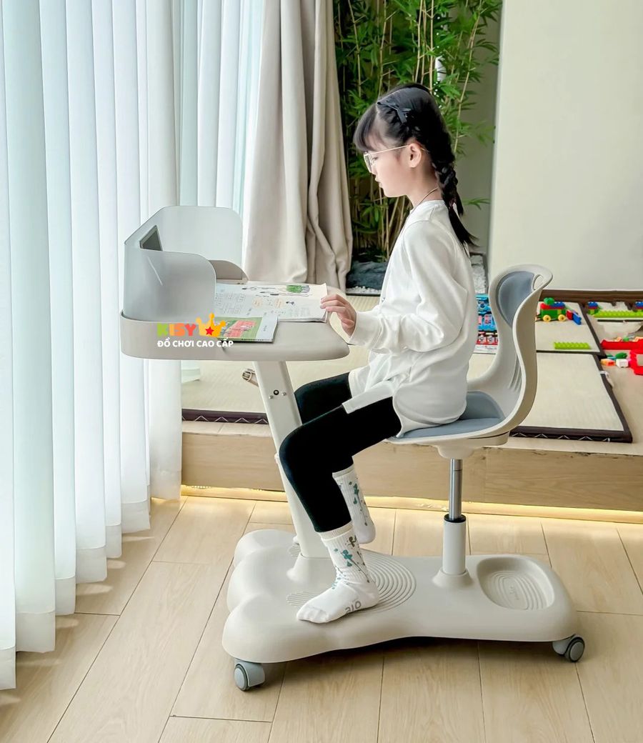 Bé ngồi học nhìn nghiêng, hai chân đặt trên chân đế