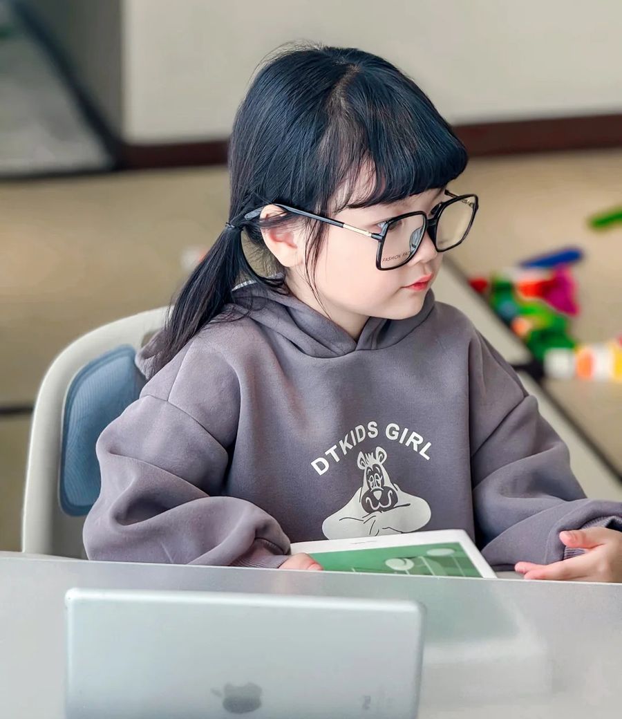 Bé ngồi học với máy tính bảng dựng trên bàn