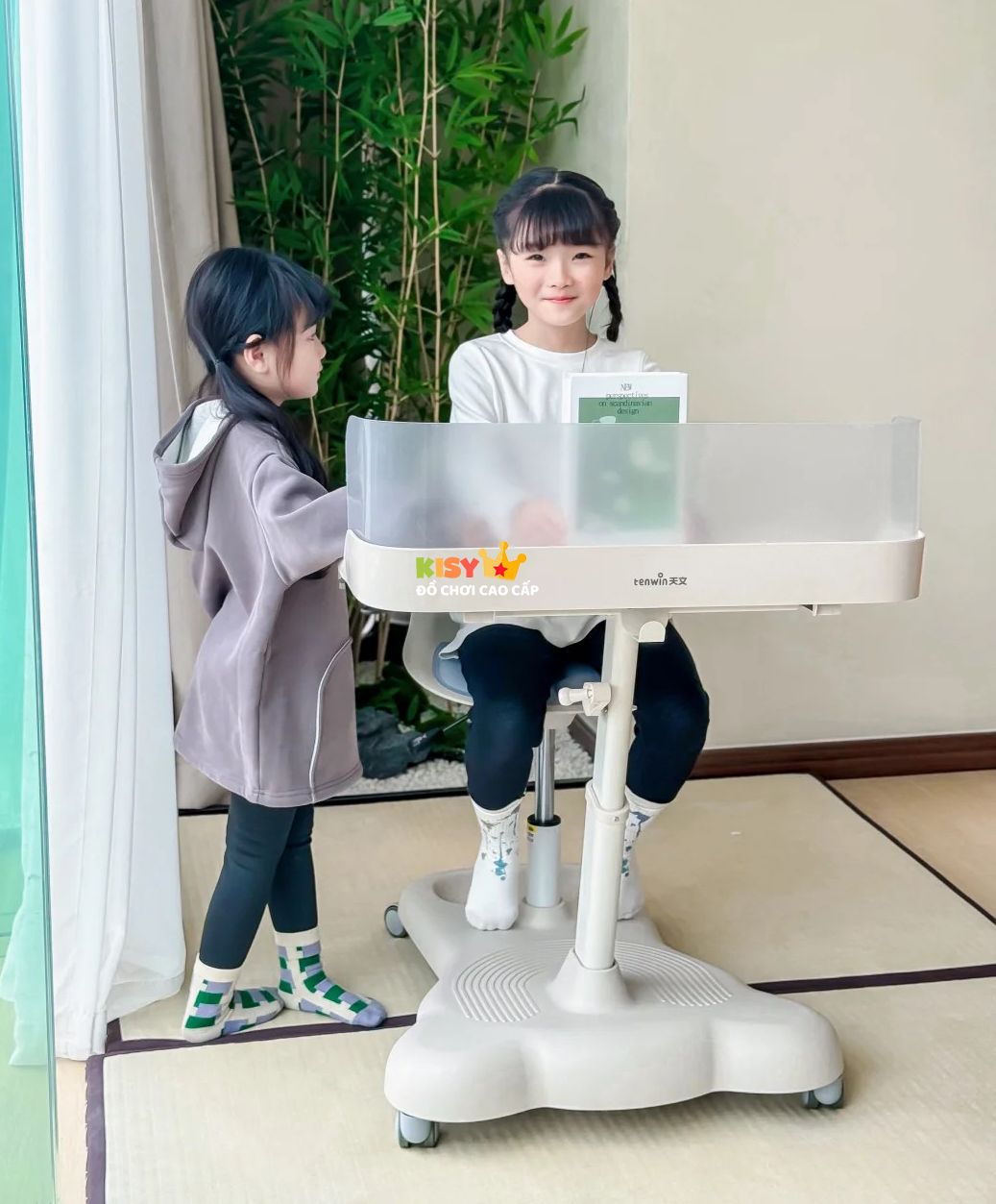 Hai chị em cùng dùng bàn học di động cạnh cửa sổ